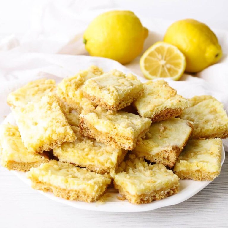 plate of lemon bars with lemons in the background